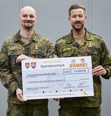 Zwei Soldaten mit Spendenscheck