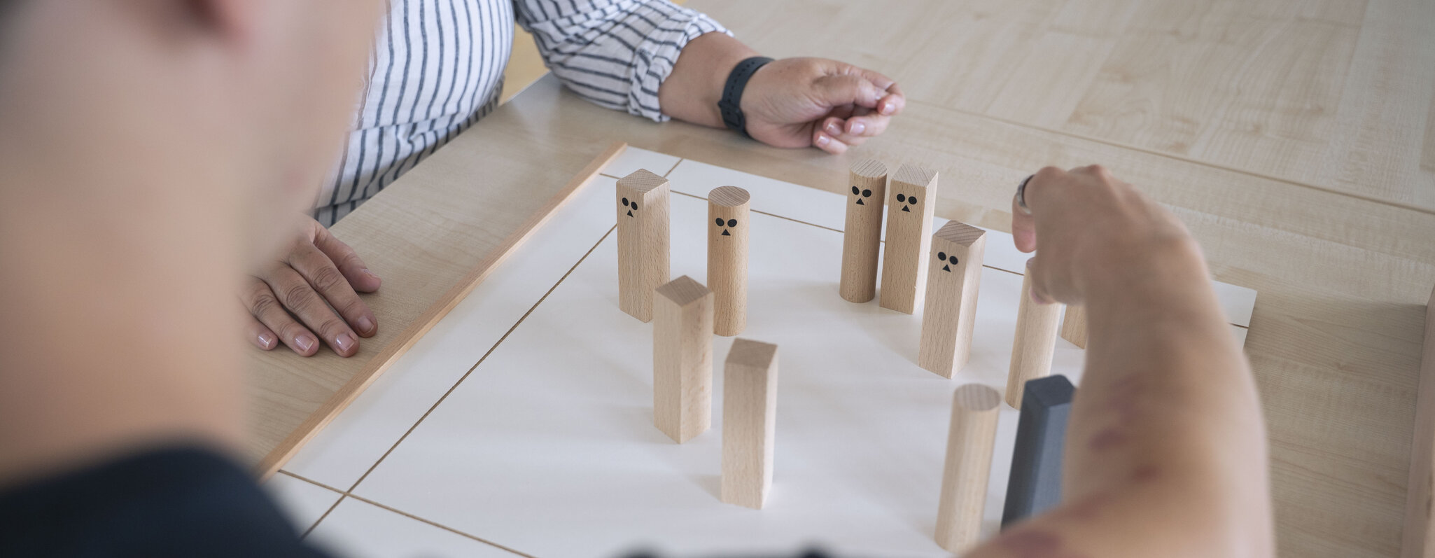 Close-Up von zwei Handpaaren beim Rollenspiel mit bemalten Holzklötzen