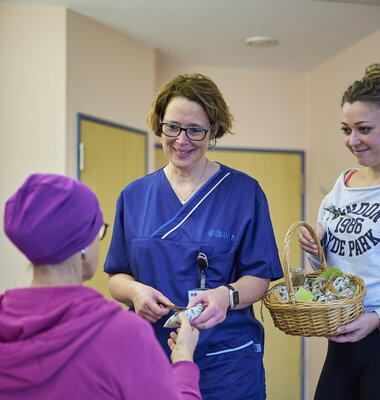 Pflegekr&auml;fte &uuml;bergeben ein Geschenk an eine Patientin