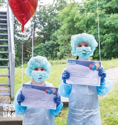 Zwei Kinder in OP-Überziehkleidung